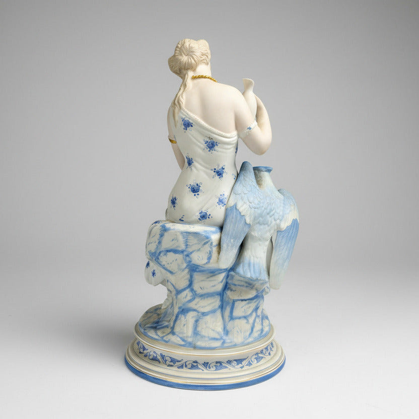 Porcelain figurine of a seated figure with blue floral patterns on a gray background