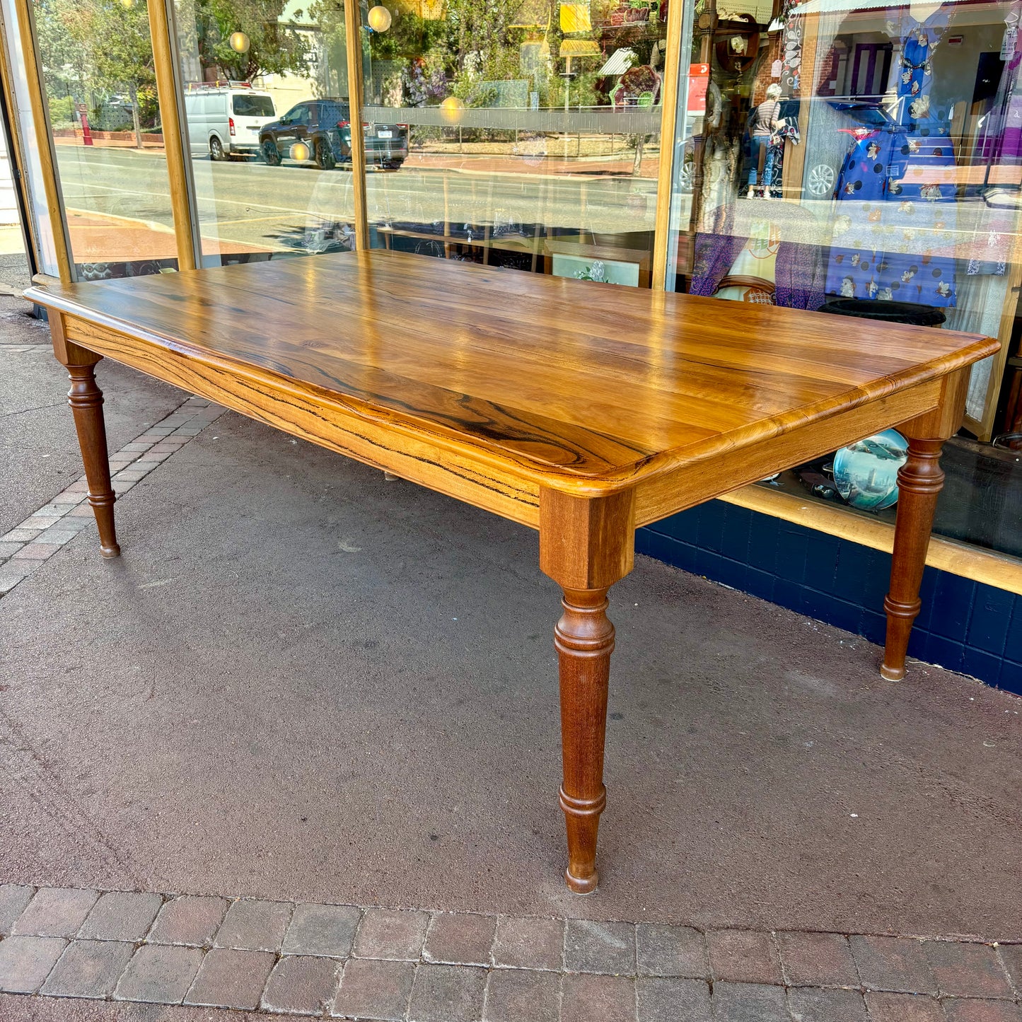 Wooden dining table on a sidewalk with a store in the background
