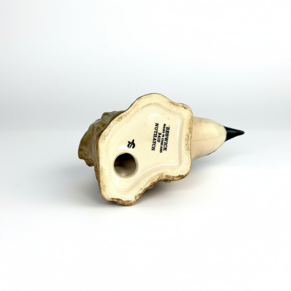 Decorative item resembling a bird on a rock with a white label on a gray background