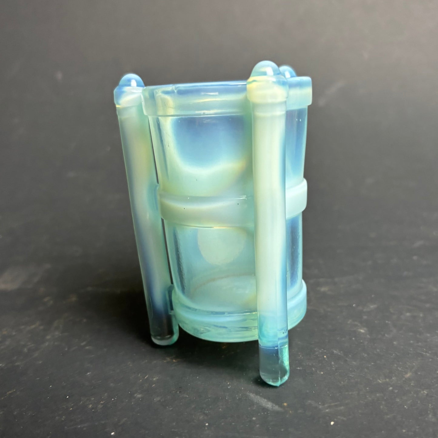 Transparent blue container with a handle on a dark gray background