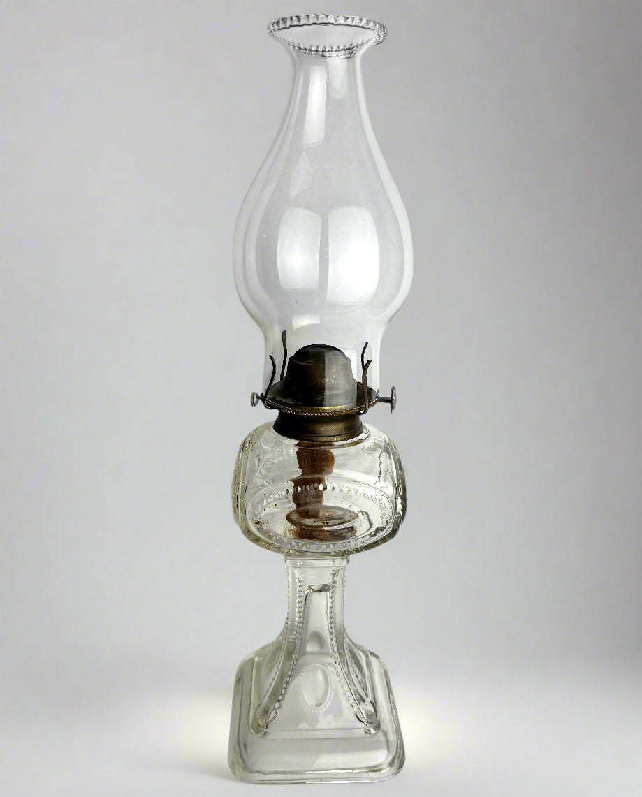Clear glass oil lamp on a light gray background