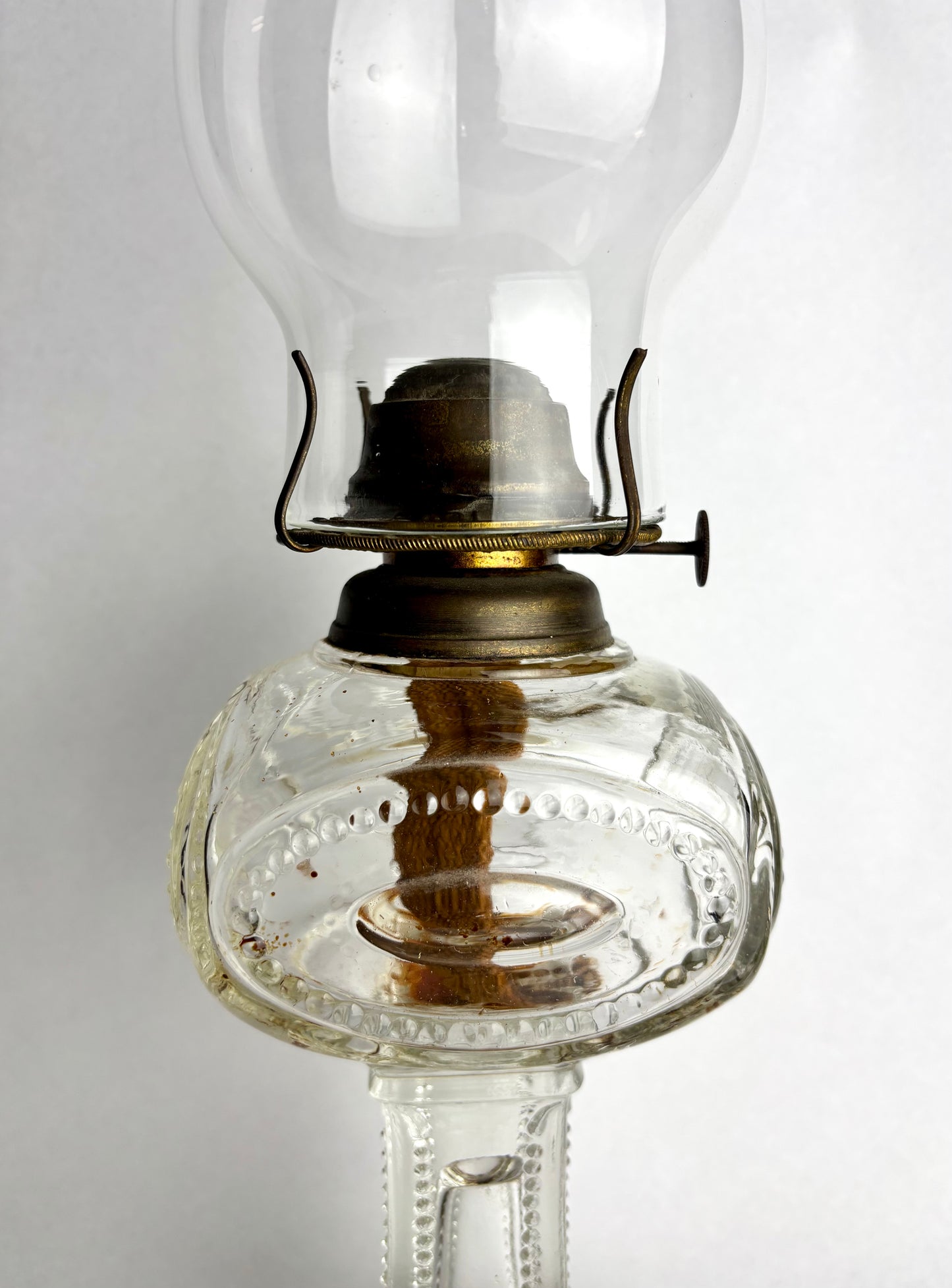 Vintage-style oil lamp with clear glass and brass accents on a white background