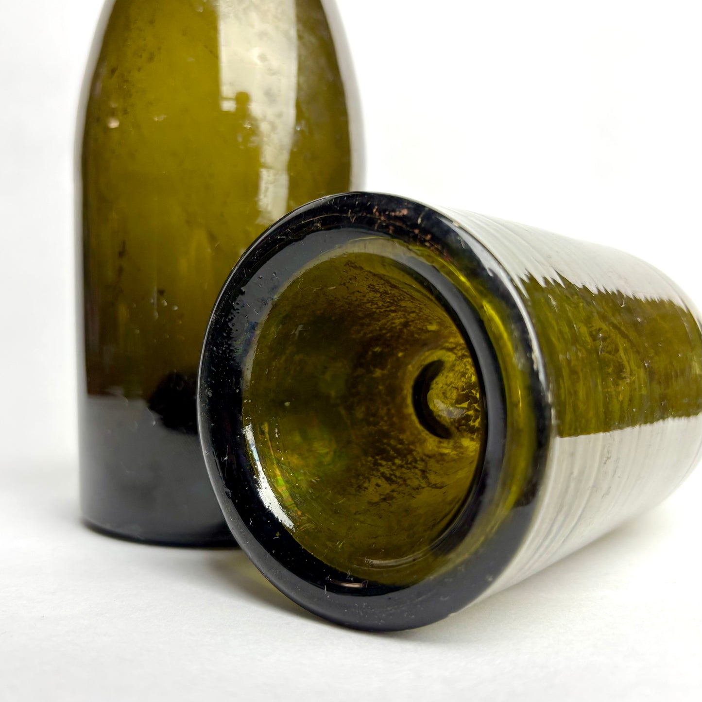 Two green glass bottles on a white background