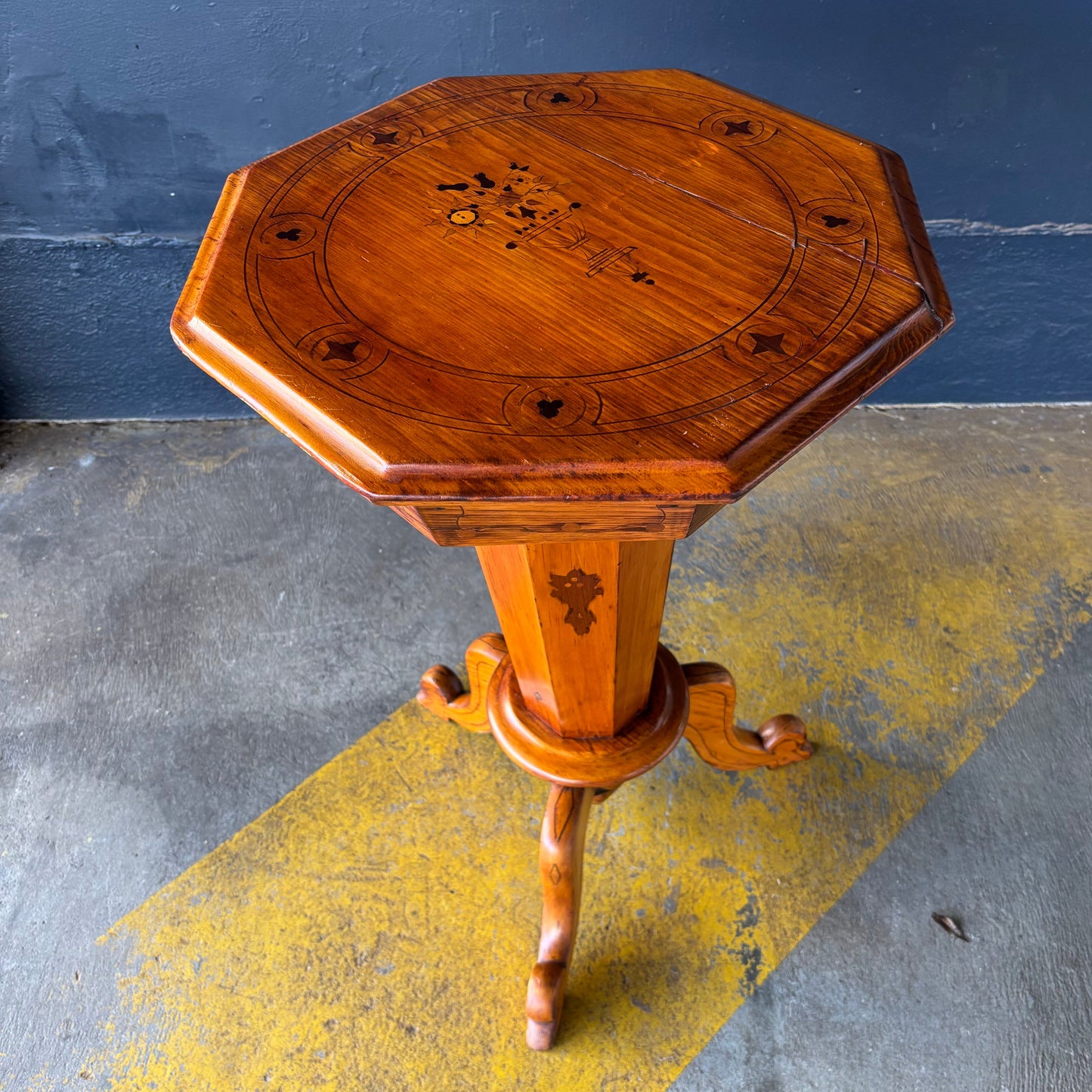 Wooden octagonal table with intricate design on a gray and yellow floor.