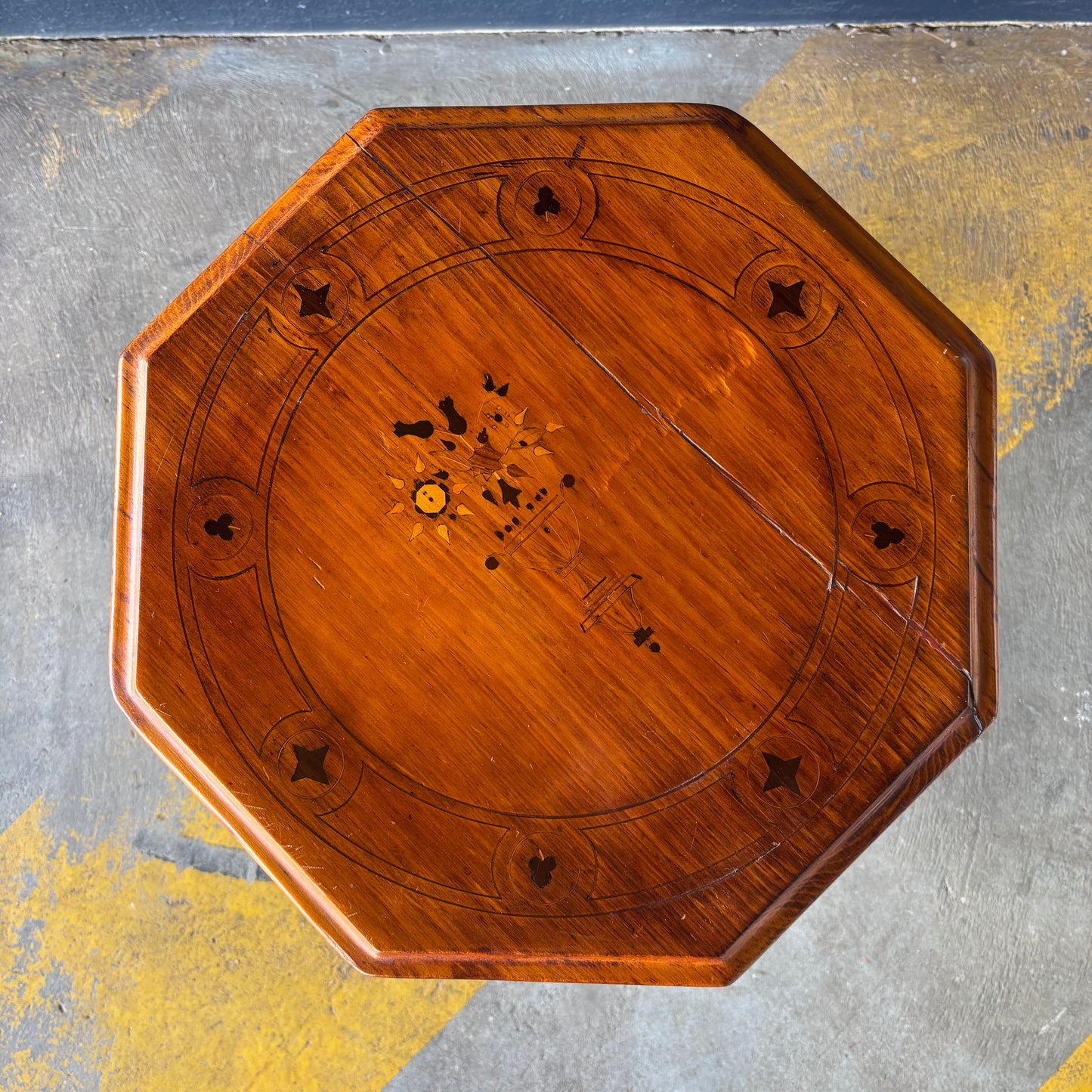 Wooden octagonal table top with decorative inlay on a textured surface
