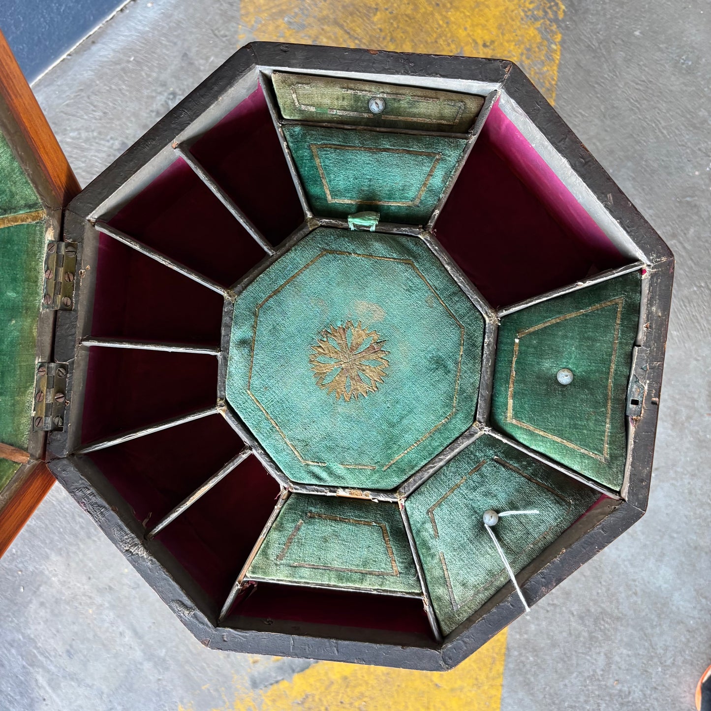 Decorative hexagonal box with green velvet interior on a textured surface