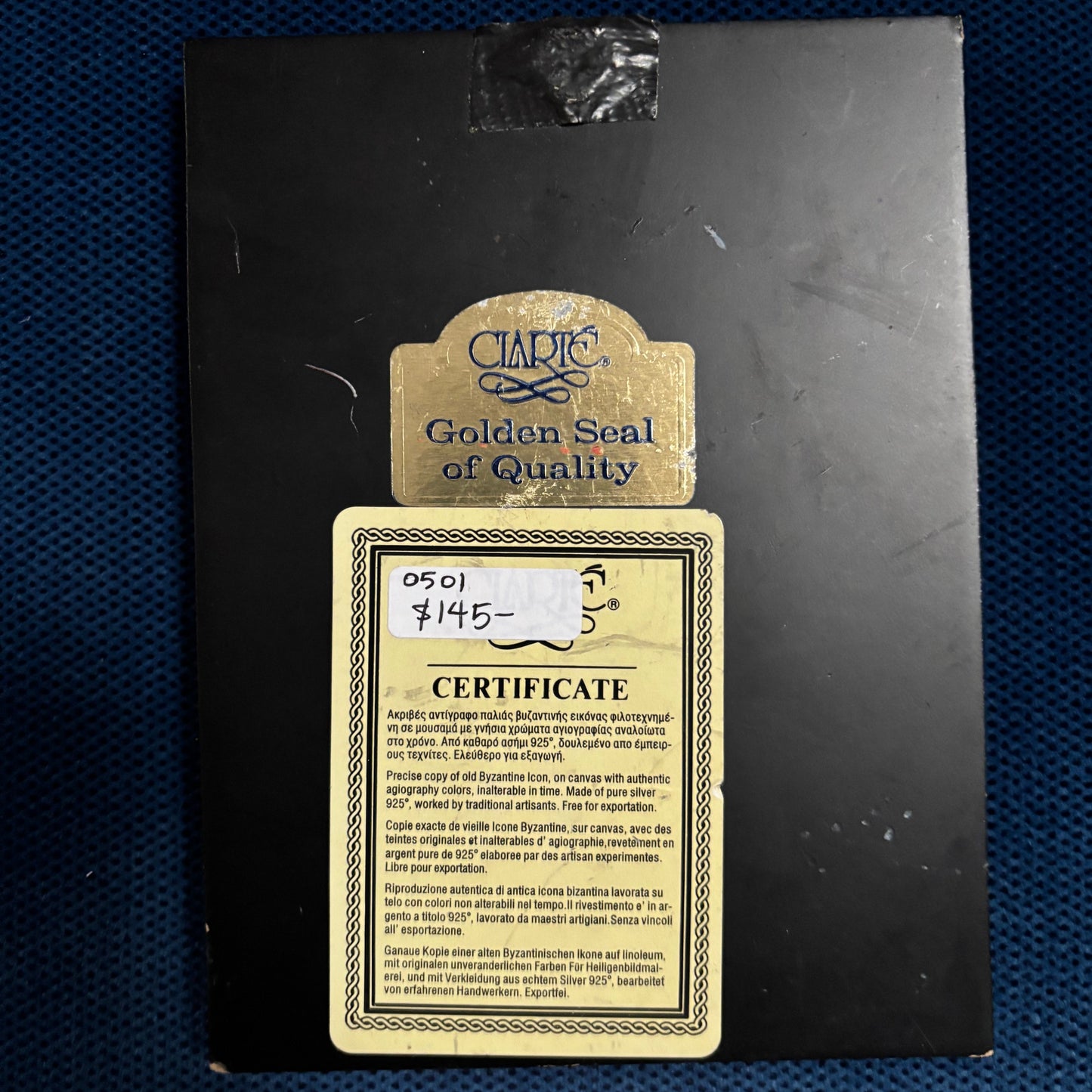 Black box with gold label and certificate on a blue textured background
