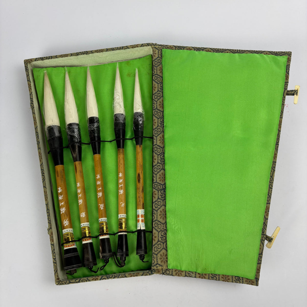 Five Chinese calligraphy brushes in green brocade case, view 1