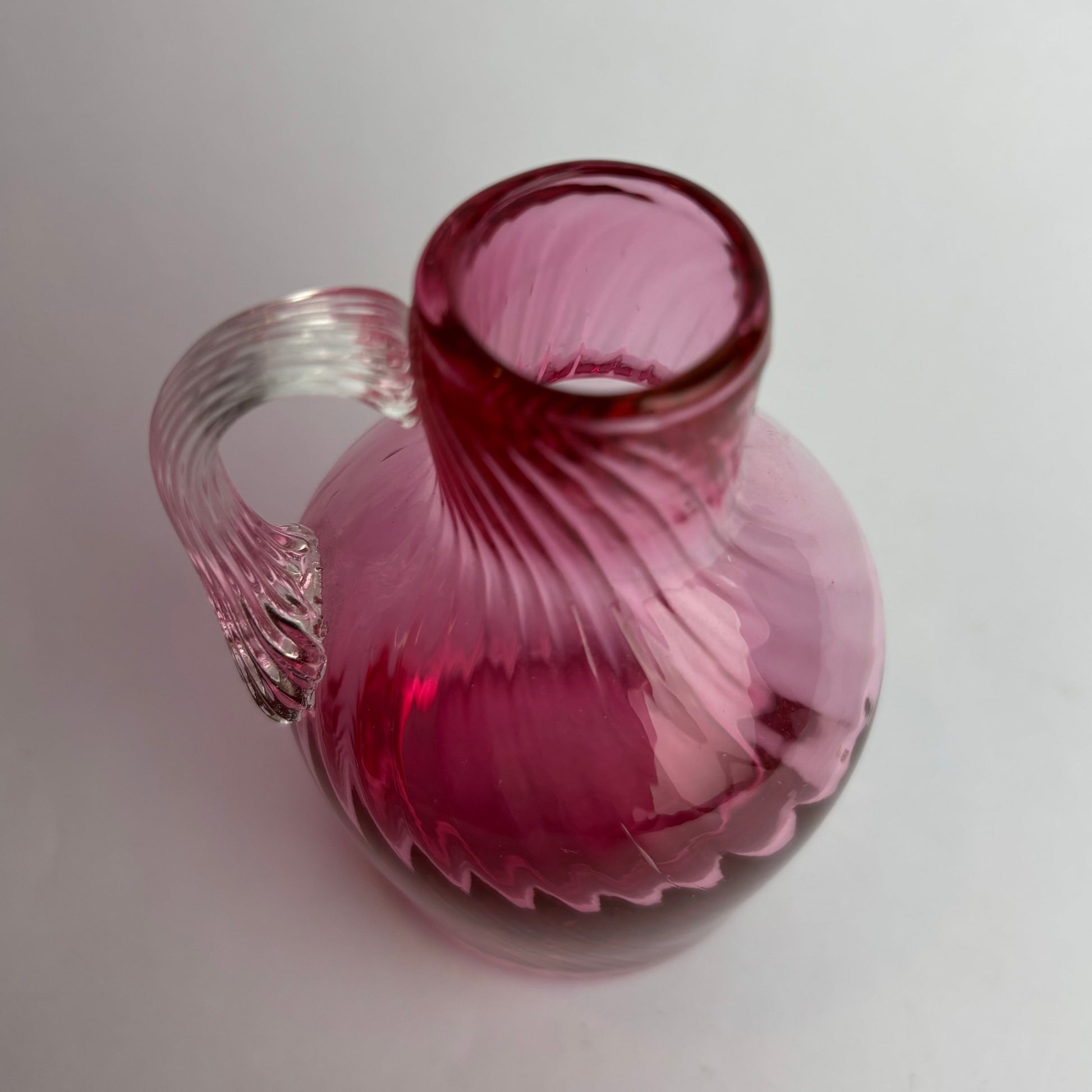 Pink glass vase with ribbed texture on a light gray background