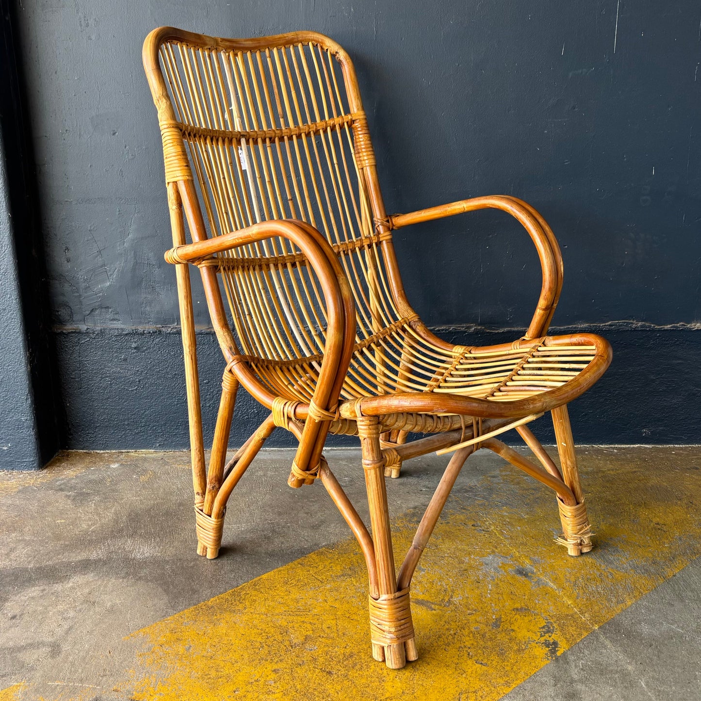Wicker chair against a dark gray wall with a yellow stain on the floor.