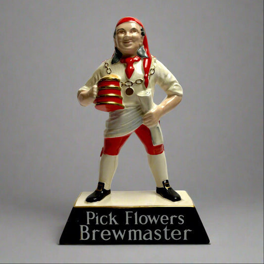 Statue of a brewmaster with a red hat and striped shirt on a gray background