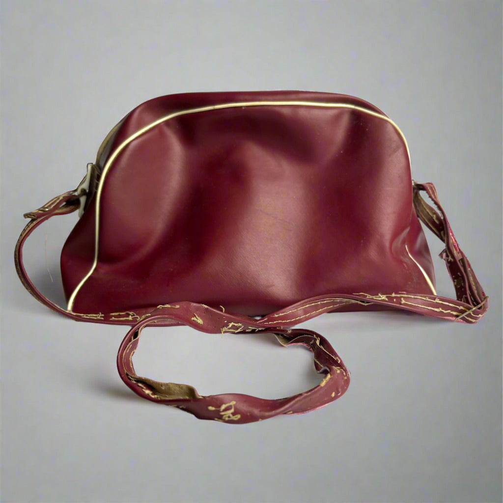 Maroon leather handbag with gold trim on a white background