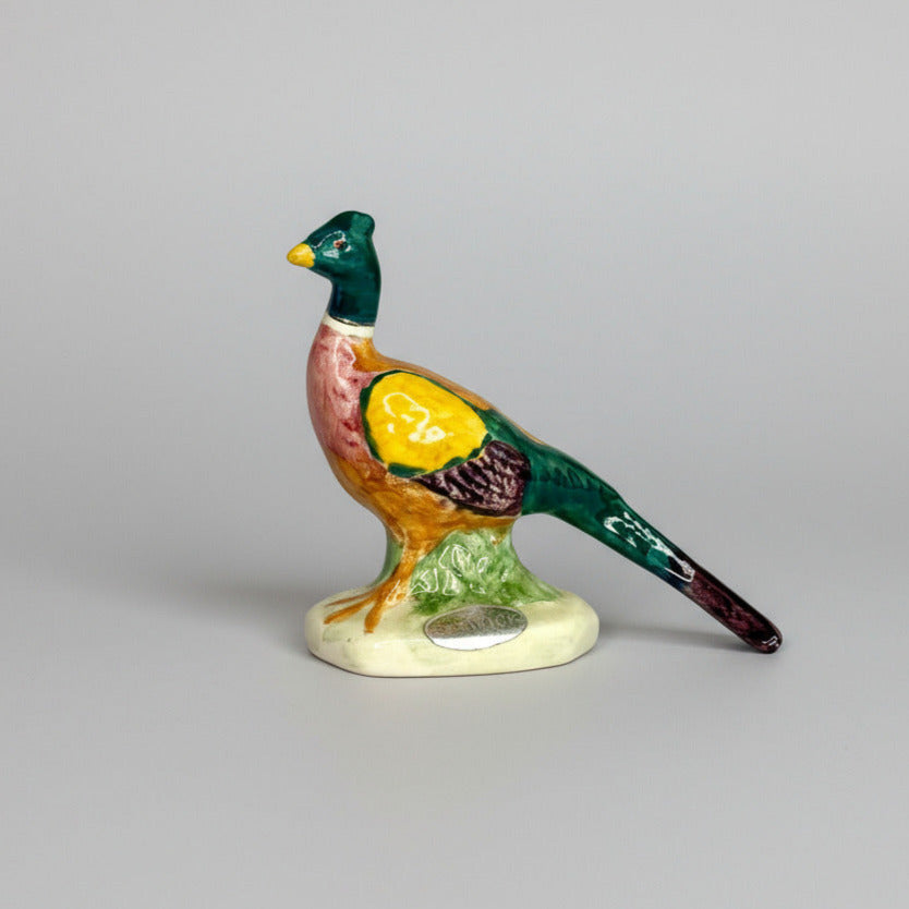 Colorful ceramic pheasant figurine on a gray background