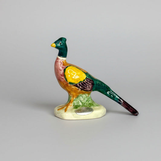 Colorful ceramic pheasant figurine on a gray background