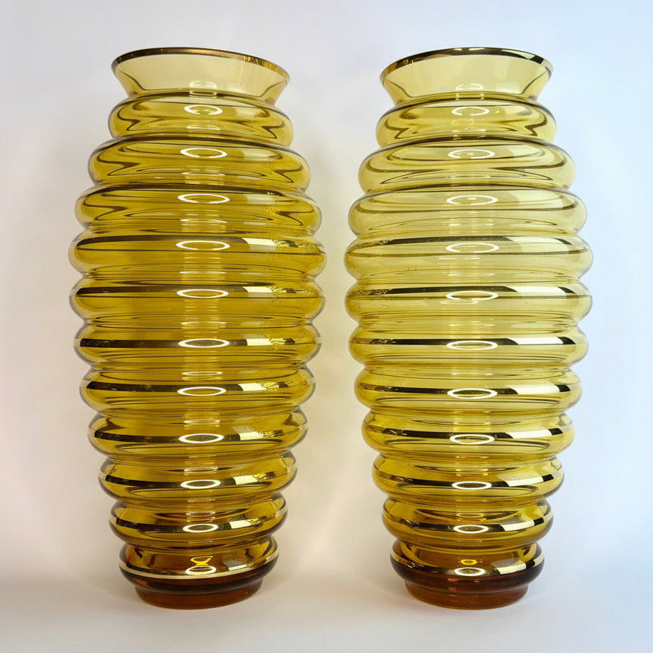 Two yellow ribbed glass vases on a white background