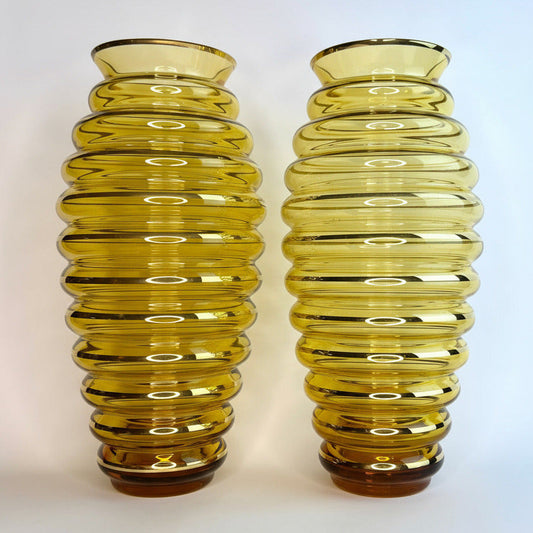 Two yellow ribbed glass vases on a white background