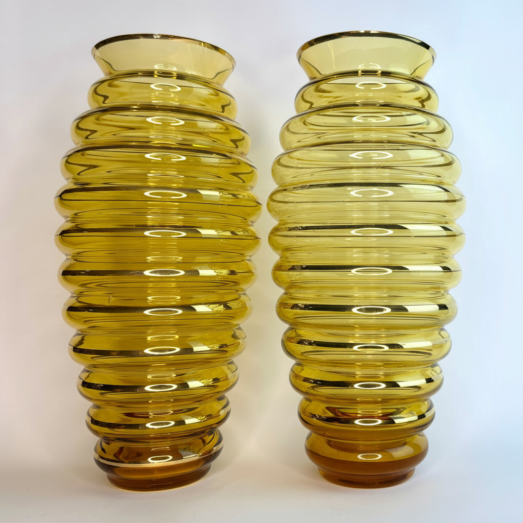 Two yellow glass vases with ribbed design on a white background