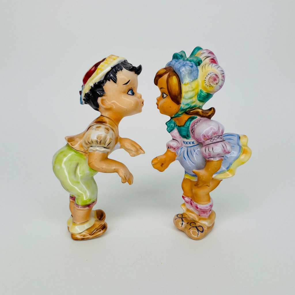 Two colorful figurines of a boy and girl facing each other on a light gray background