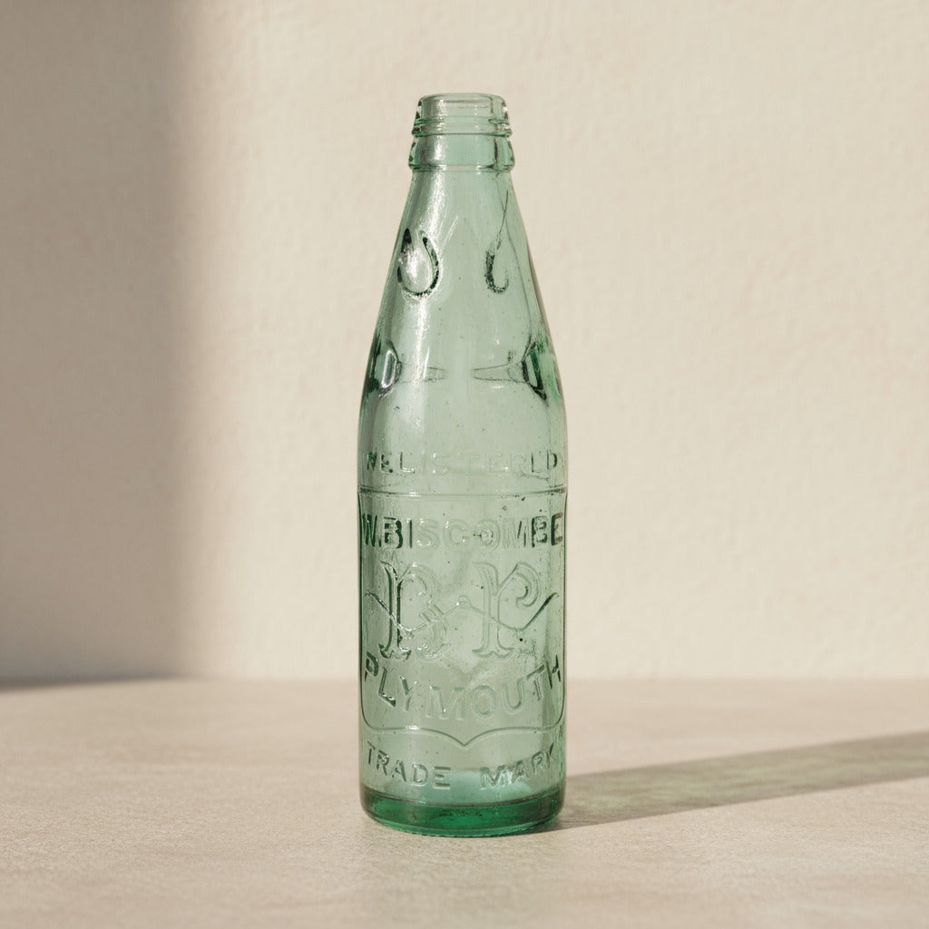 Vintage green glass bottle with embossed text on a white background