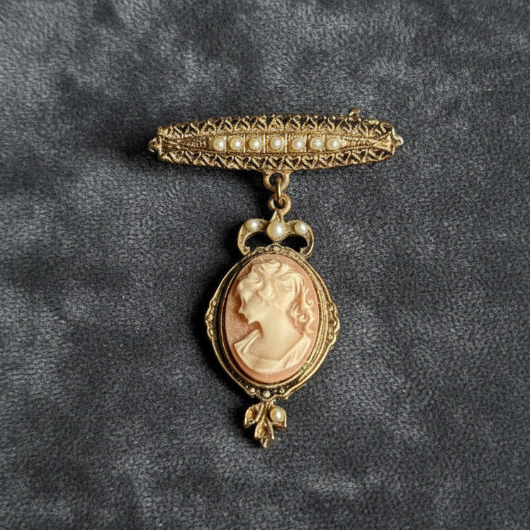 Vintage gold brooch with a cameo pendant on a gray textured background