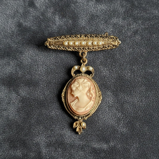 Vintage gold brooch with a cameo pendant on a gray textured background