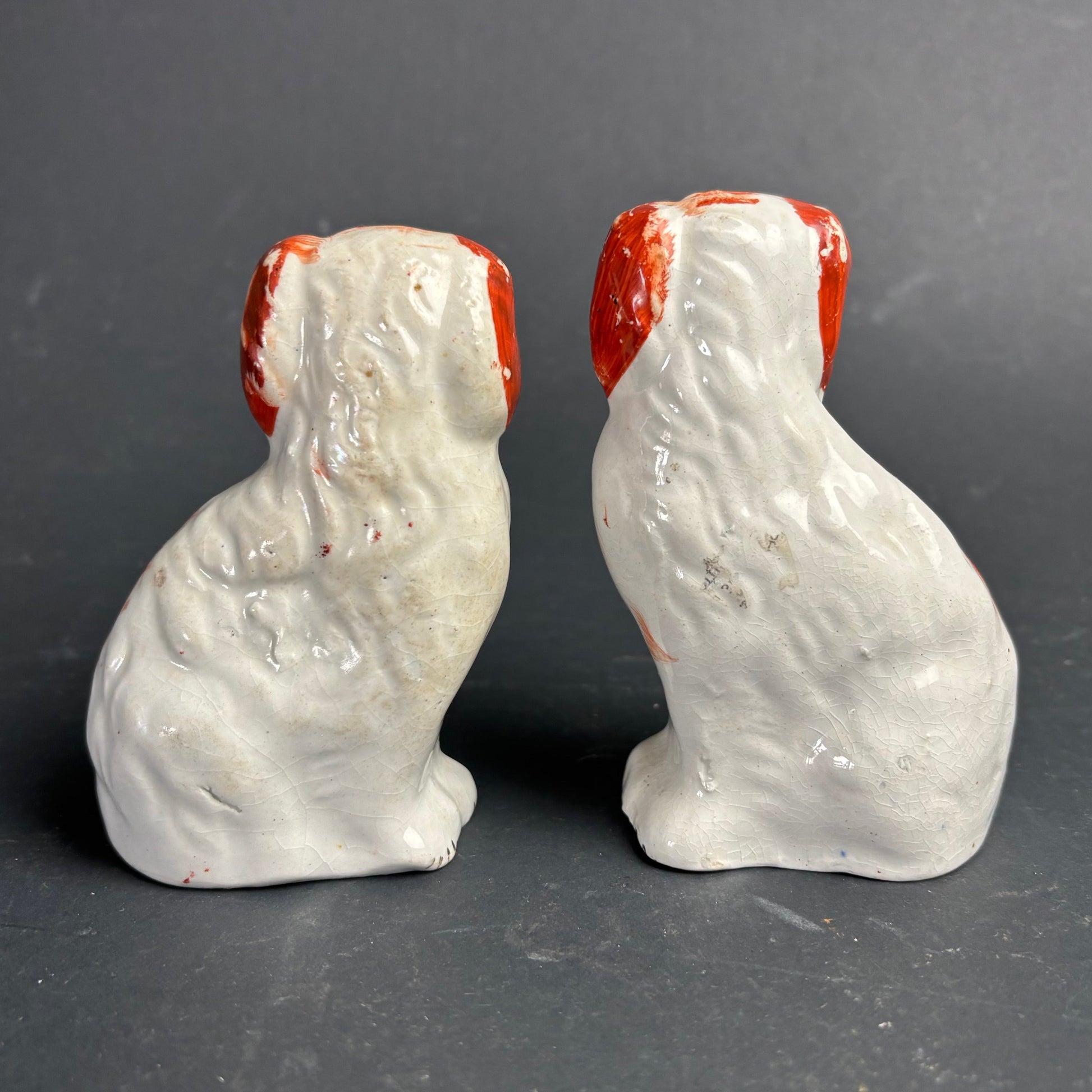 Two ceramic dog figurines with red faces on a gray background