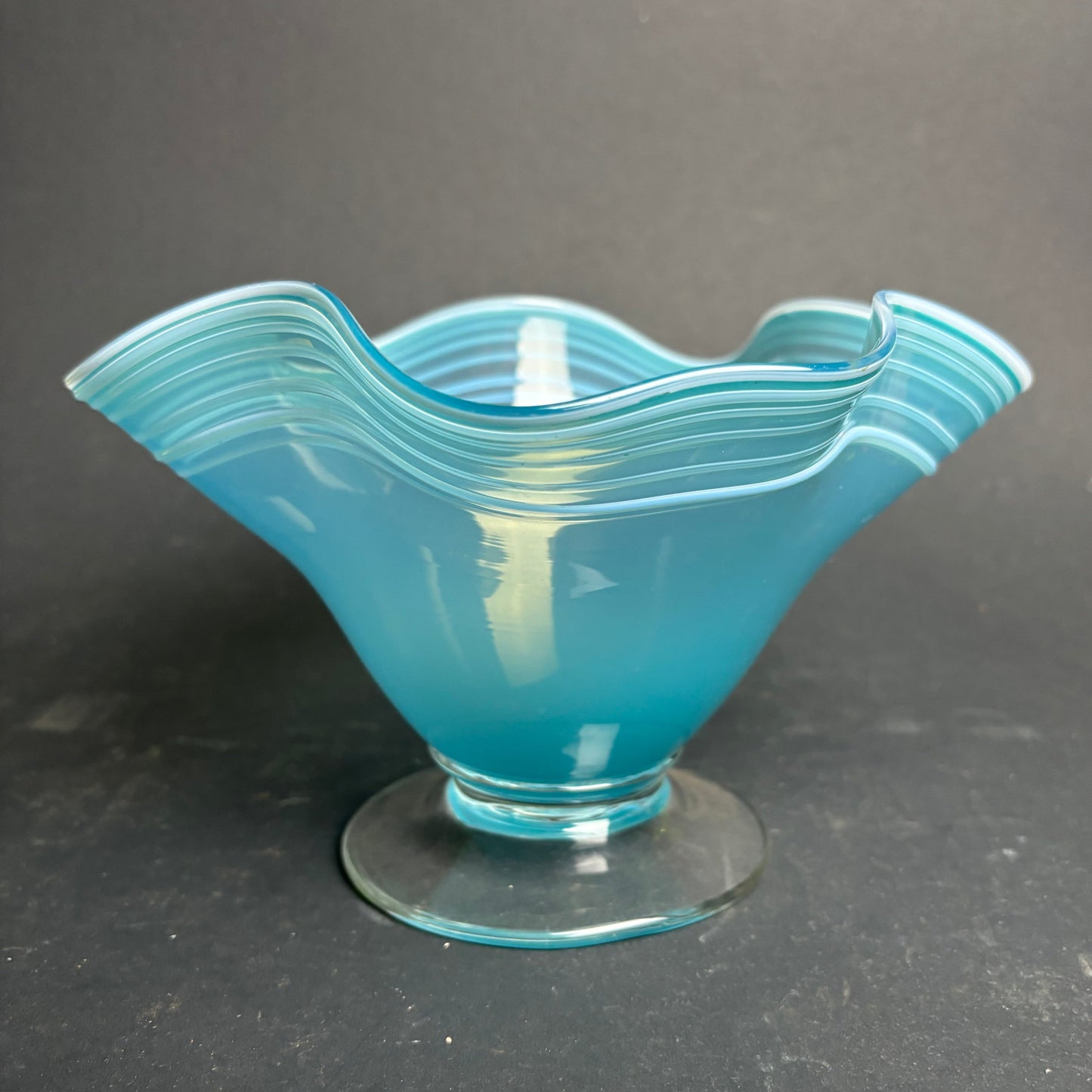 Blue glass bowl with wavy design on a dark gray background