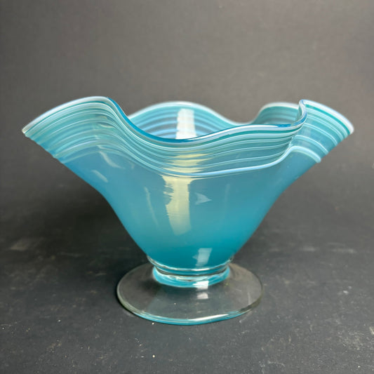 Blue glass bowl with wavy design on a dark gray background
