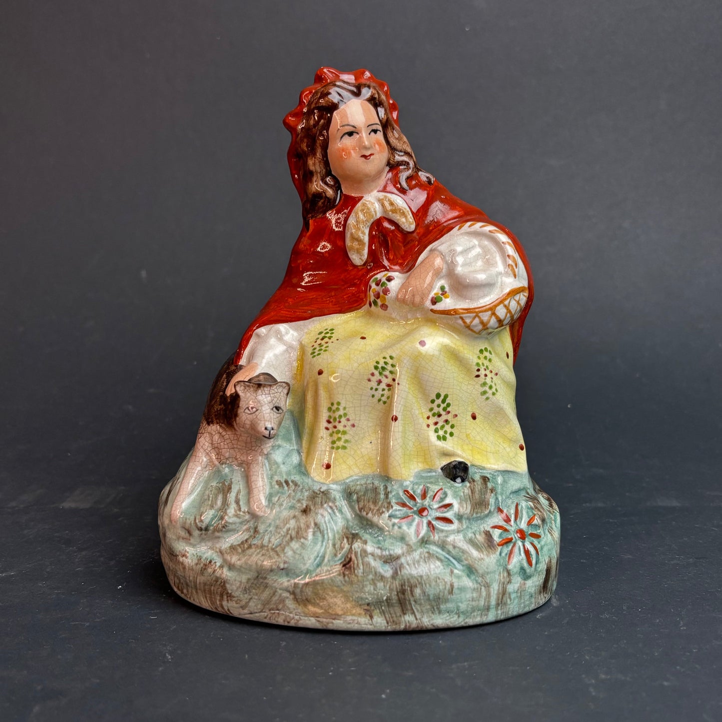 Ceramic figurine of a woman with a dog on a dark gray background