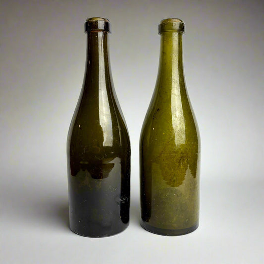 Two green glass bottles on a white background