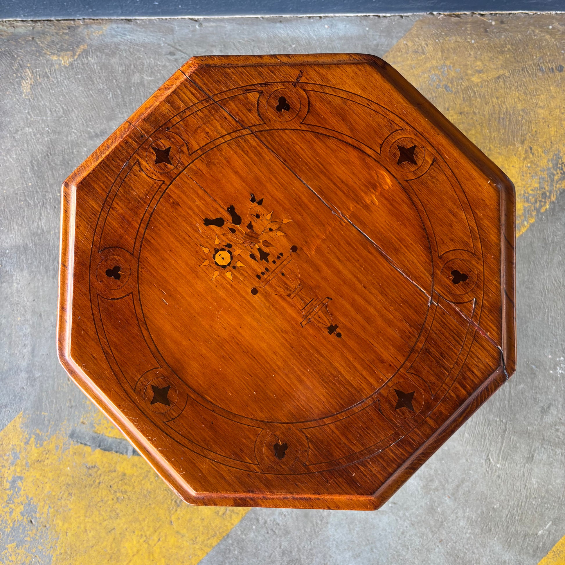 Wooden octagonal table top with decorative inlay on a textured surface