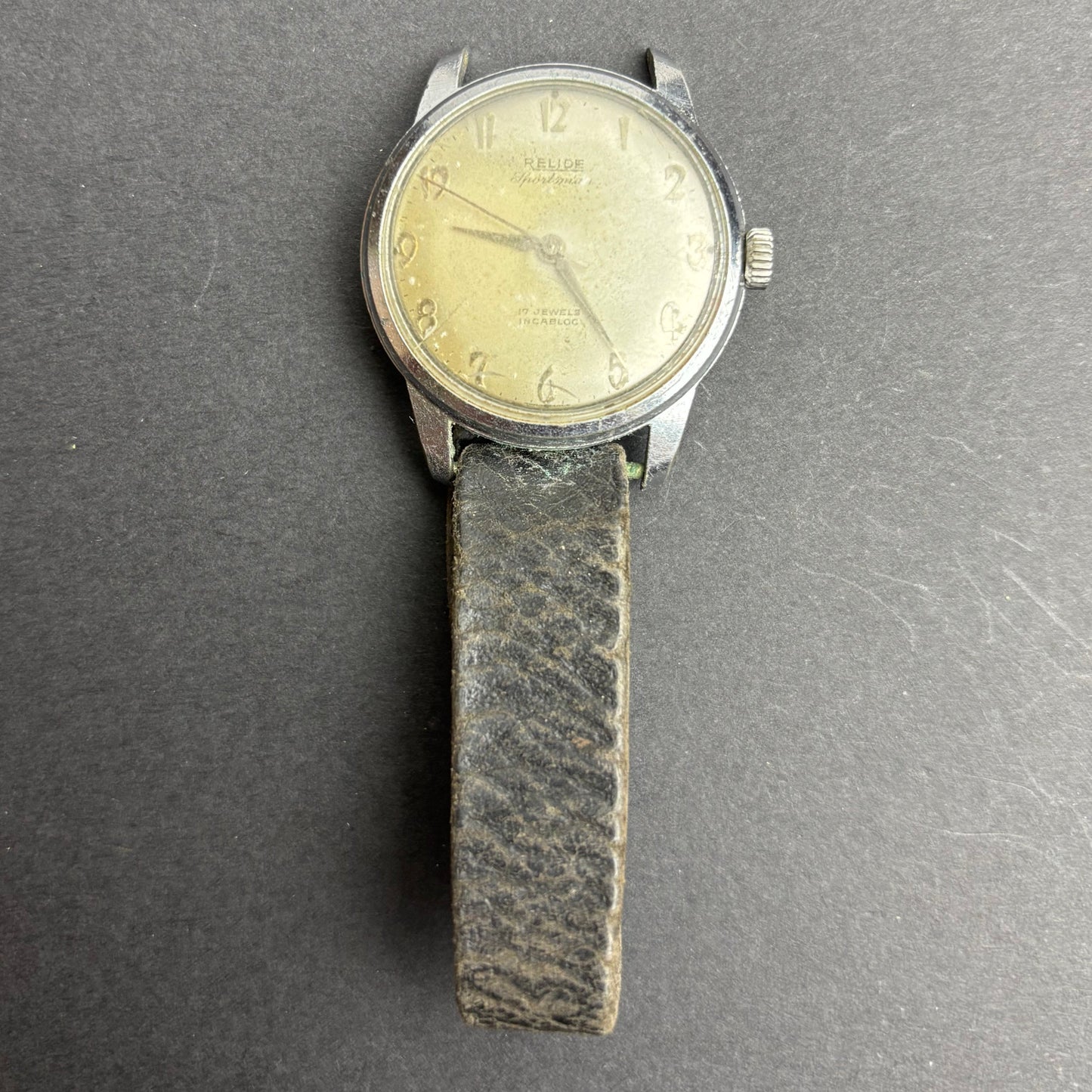 Vintage wristwatch with a leather strap on a gray background