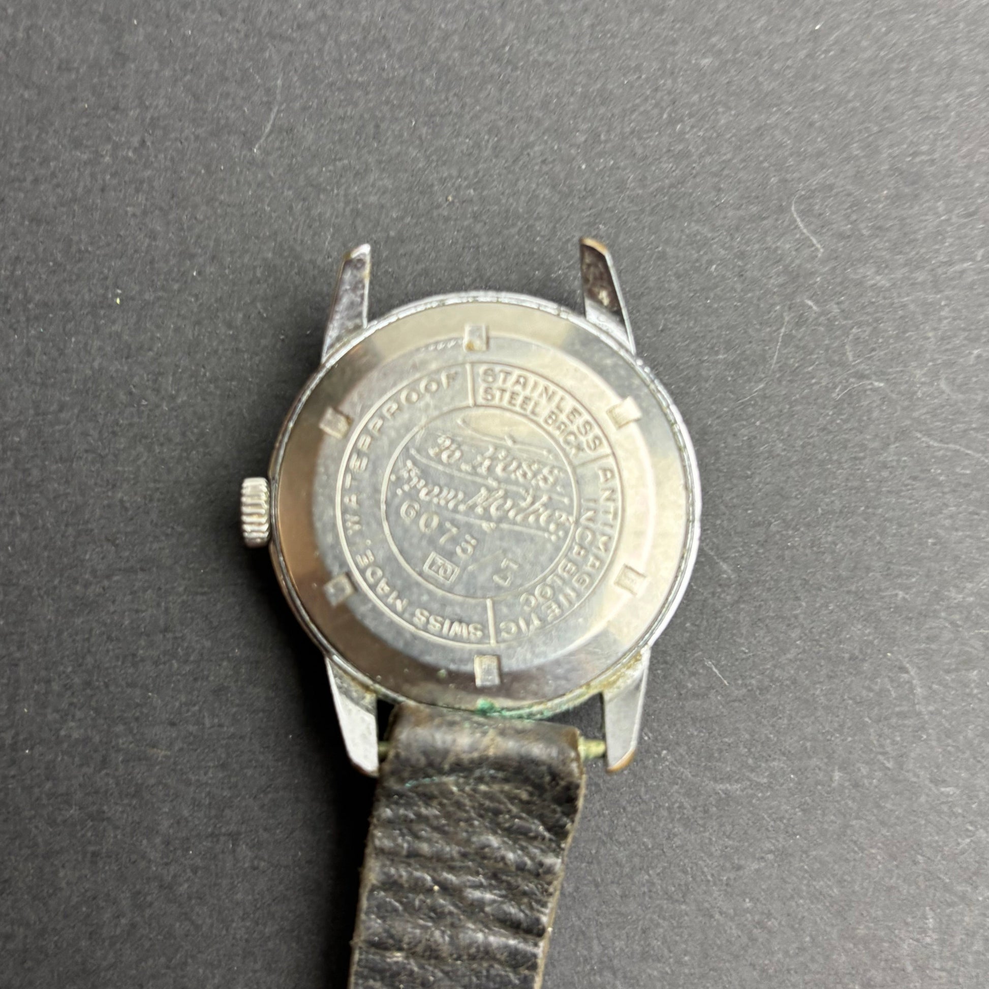 Wristwatch with a coin on a dark gray background