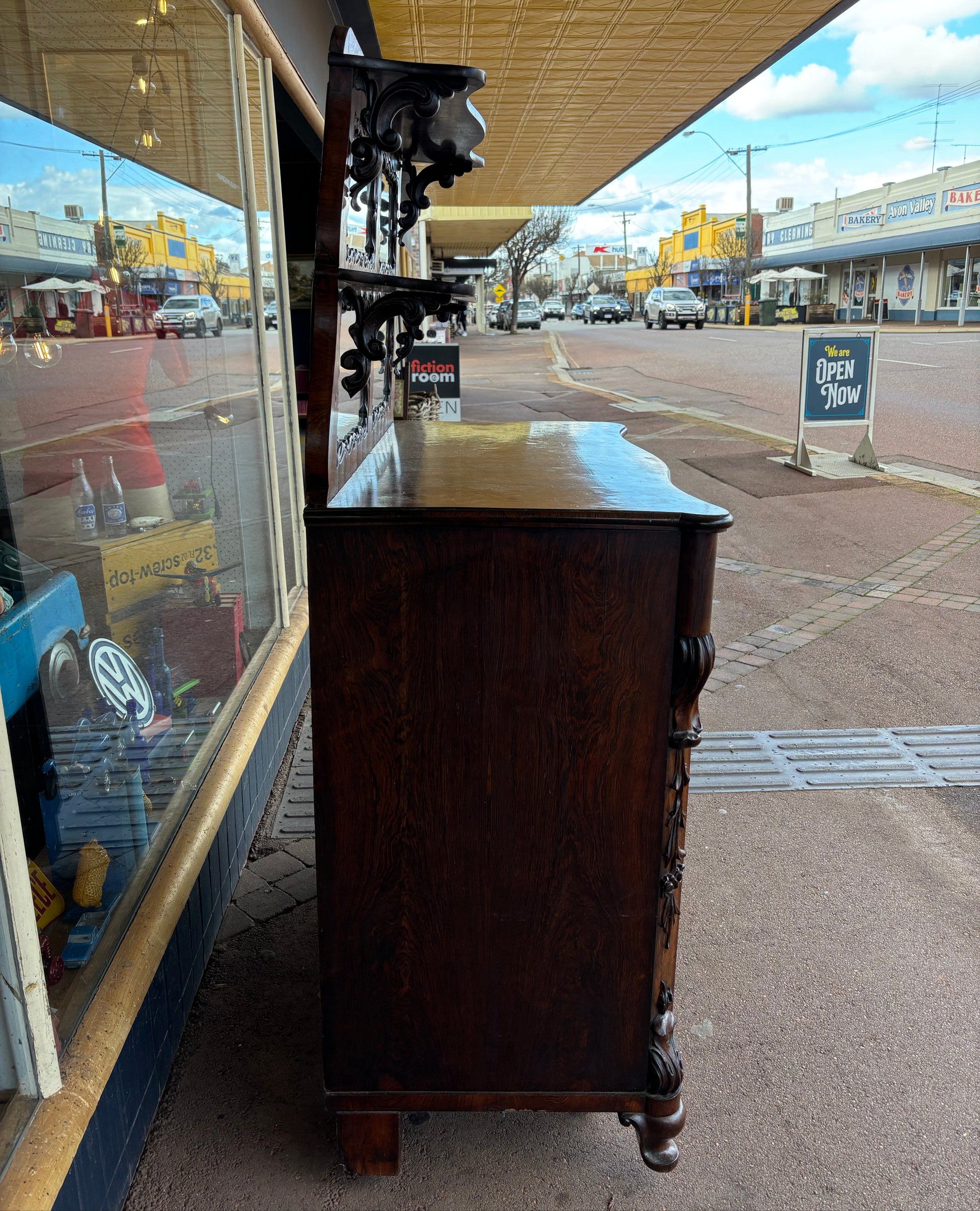 Dark wooden bench with decorative armrests on a sidewalk