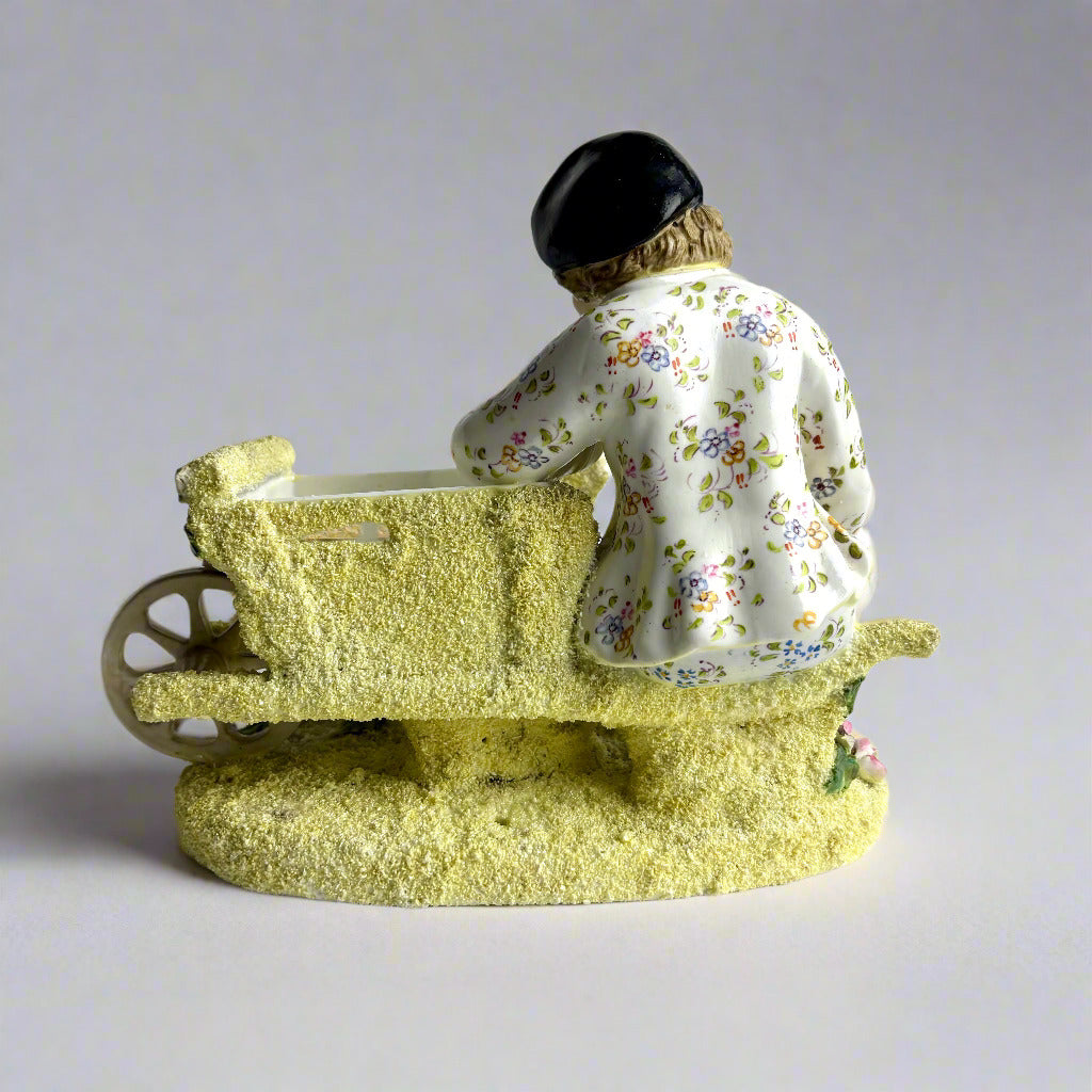 Vintage ceramic figure of a child with a wheelbarrow on a white background