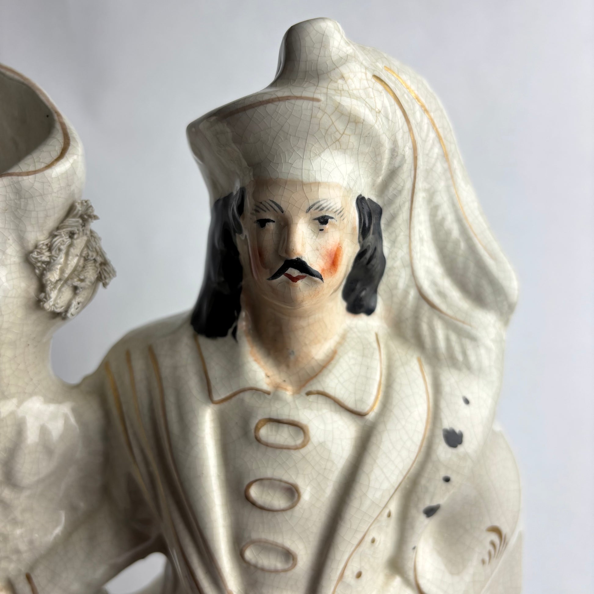 Ceramic figure of a man with a mustache and detailed clothing on a white background