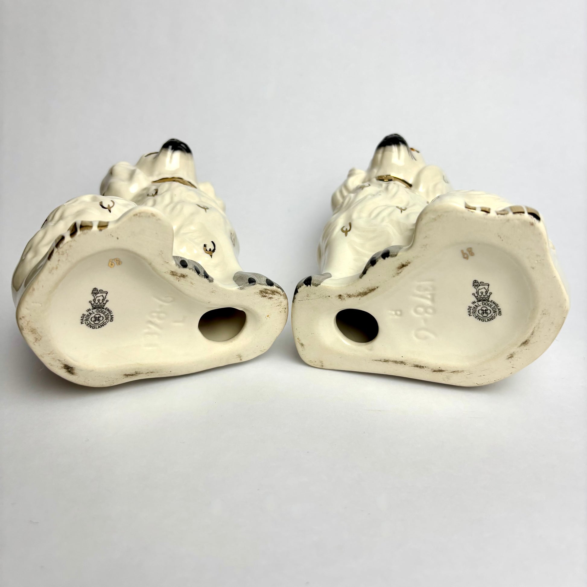 Pair of white ceramic shoes with decorative elements on a light gray background