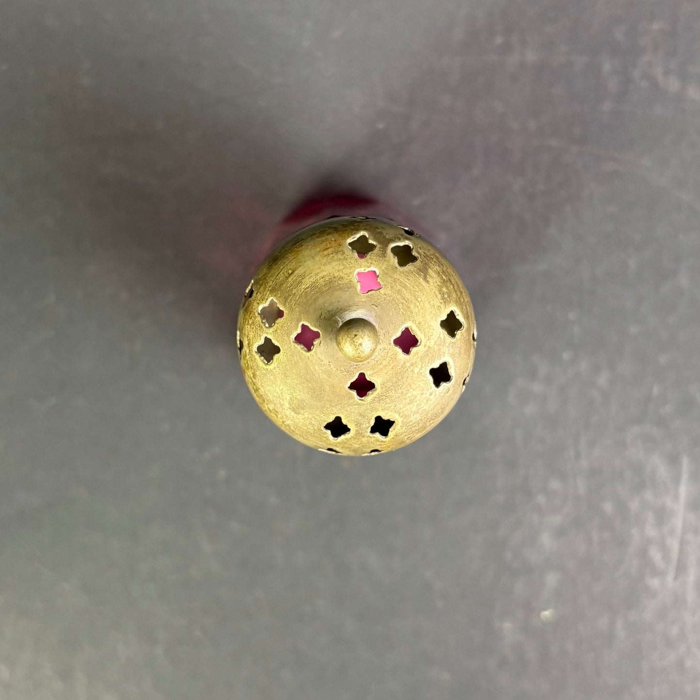 Gold-colored decorative object with cut-out patterns on a gray background