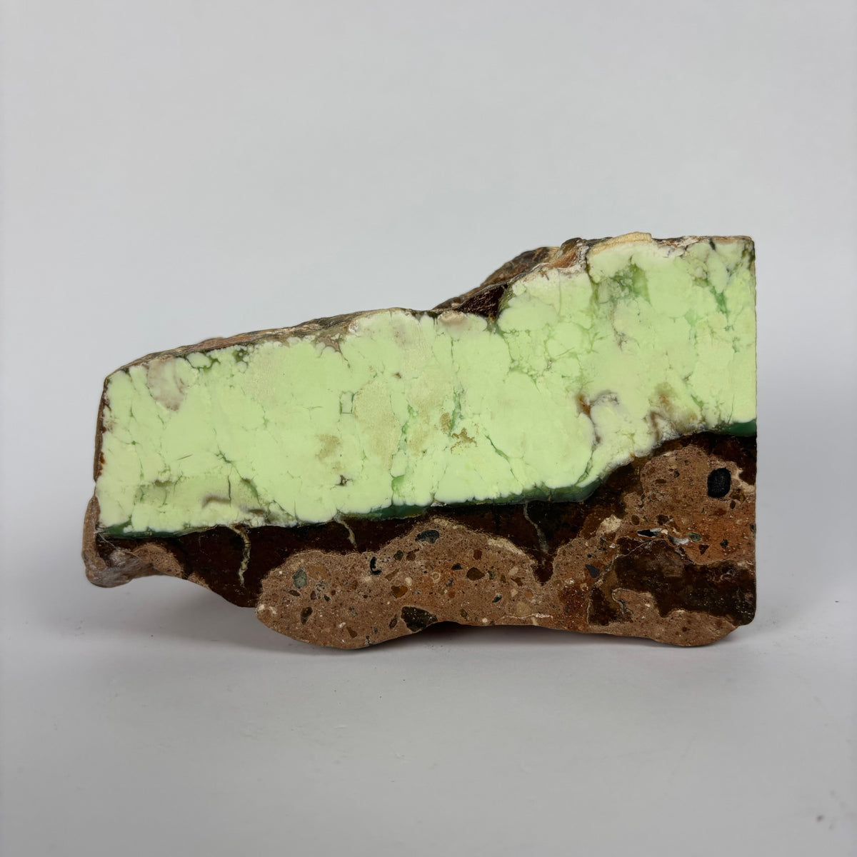 Rough pale yellow-green mineral seam in brown host rock specimen